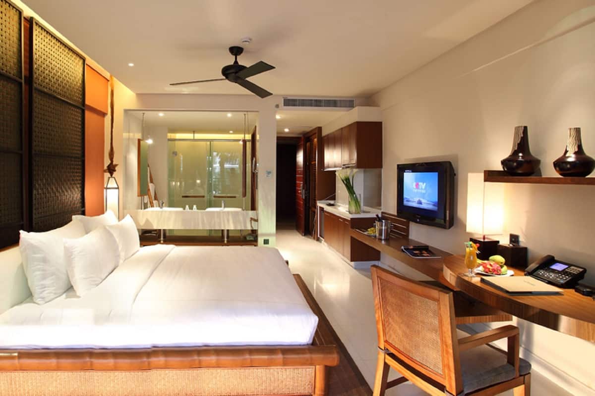 Habitación de hotel con una cama grande, un escritorio con computadora, televisor y una pequeña zona de estar.