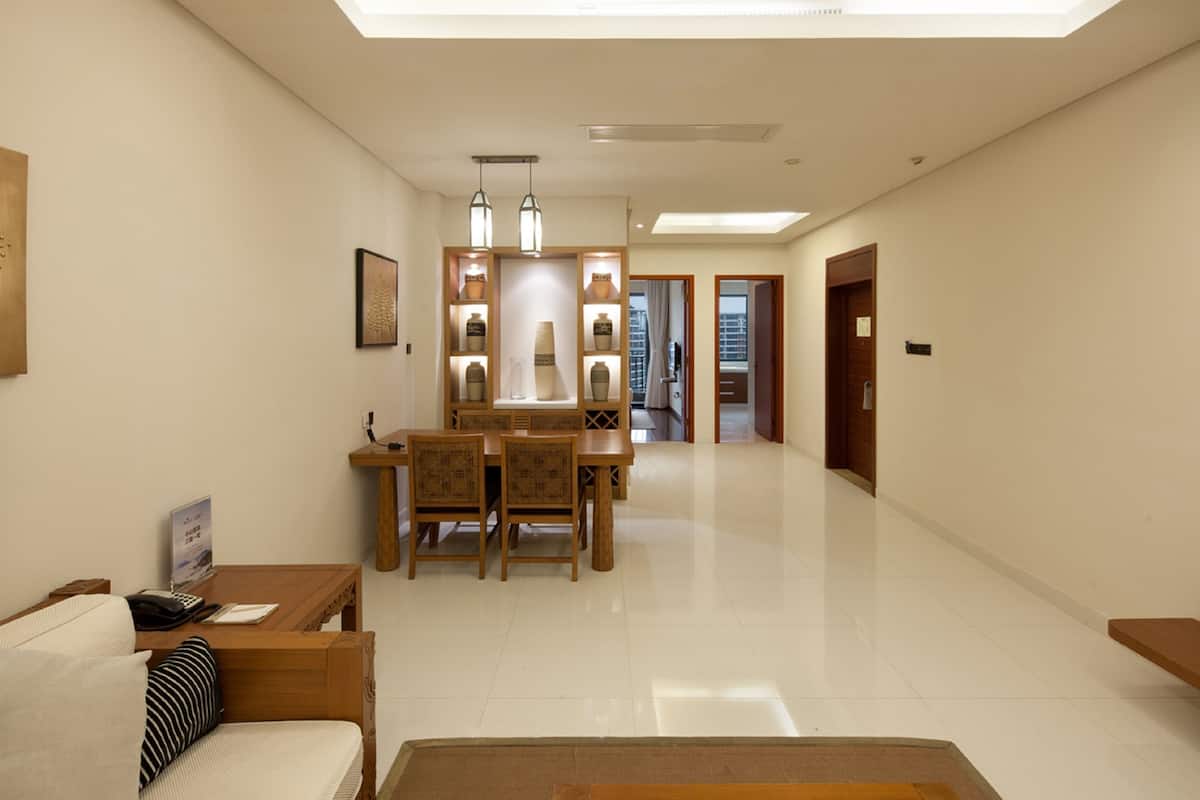 Habitación de hotel con zona de comedor, sofá y una mesita con teléfono y documentos.