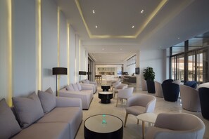 A modern hotel lobby with a sofa area, seating, a coffee table, and a view of the kitchen and bar area. - Sanya Phoenix Airport Hotel (Sanya)