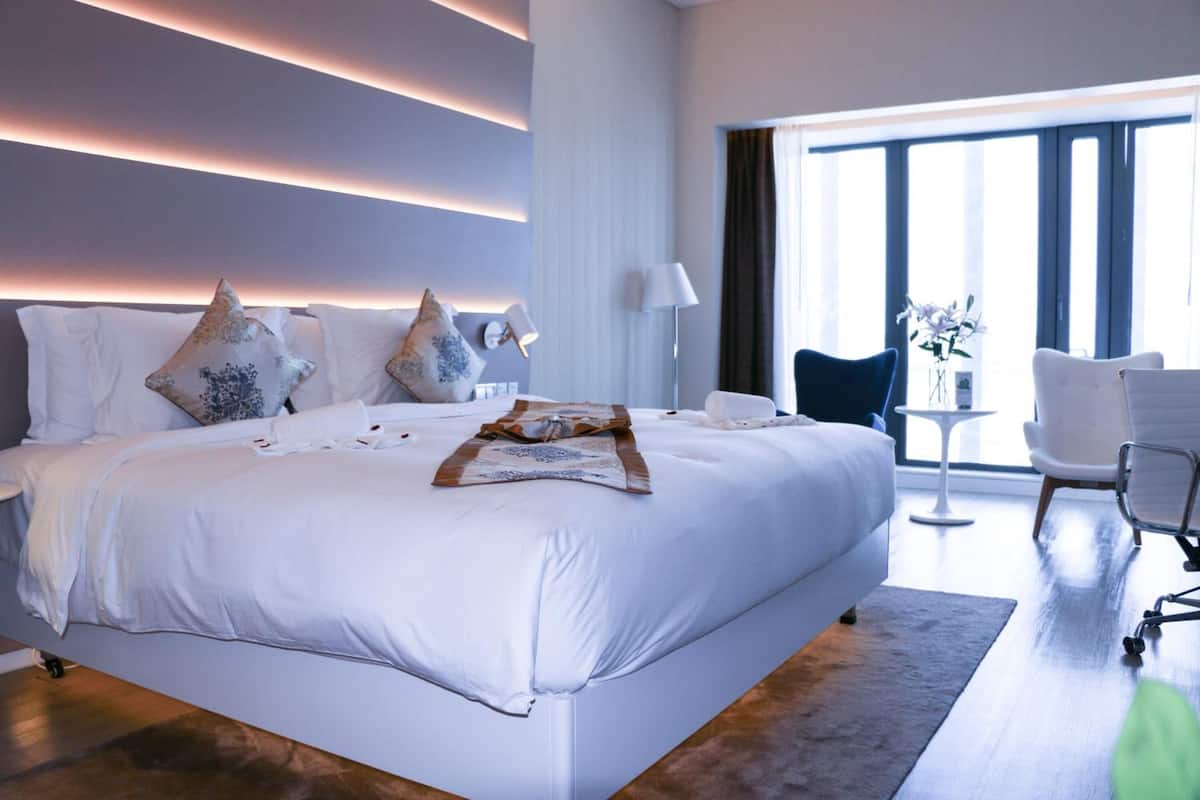A modern hotel room with a large bed, a desk, and a chair.