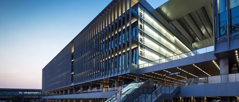 A modern building with a glass facade, multiple floors, and an outdoor area with a staircase.