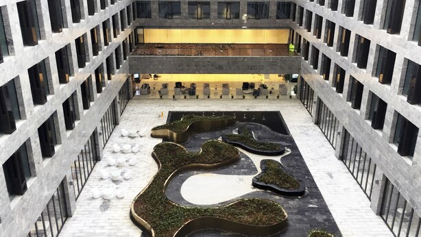 Un edificio moderno con un patio central que presenta macetas geométricas y una zona de estar.