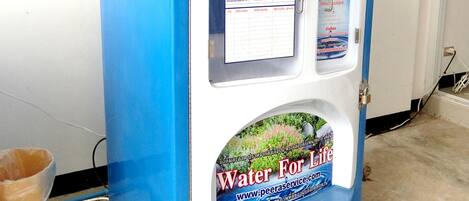 A water vending machine with a blue and white color scheme, featuring a digital display and a water bottle dispensing area.