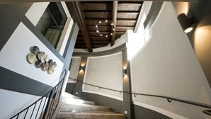 Un escalier avec un plafond en bois, un luminaire circulaire et une applique murale.