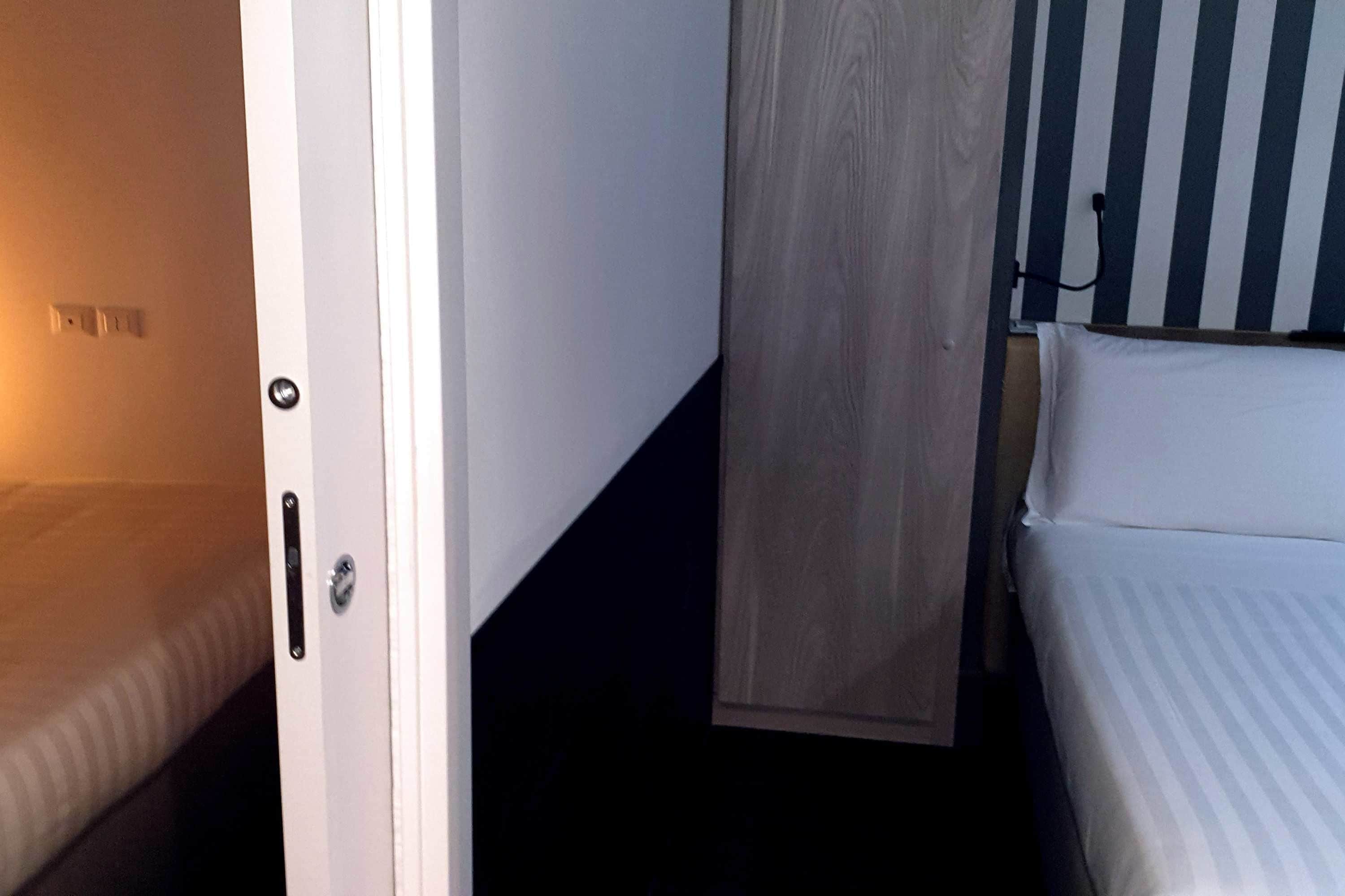 Une chambre d’hôtel avec un lit, une porte et un mur recouvert de panneaux de bois.