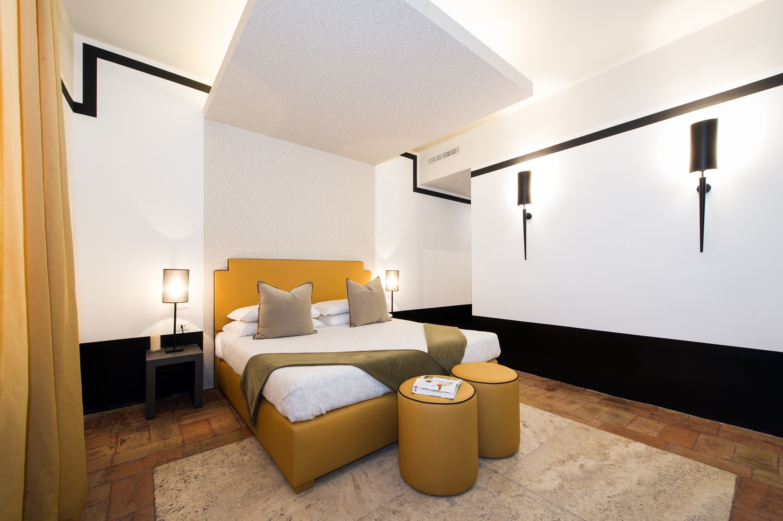 A modern hotel room with a large bed, bedside tables, a reading lamp, and a small round table.