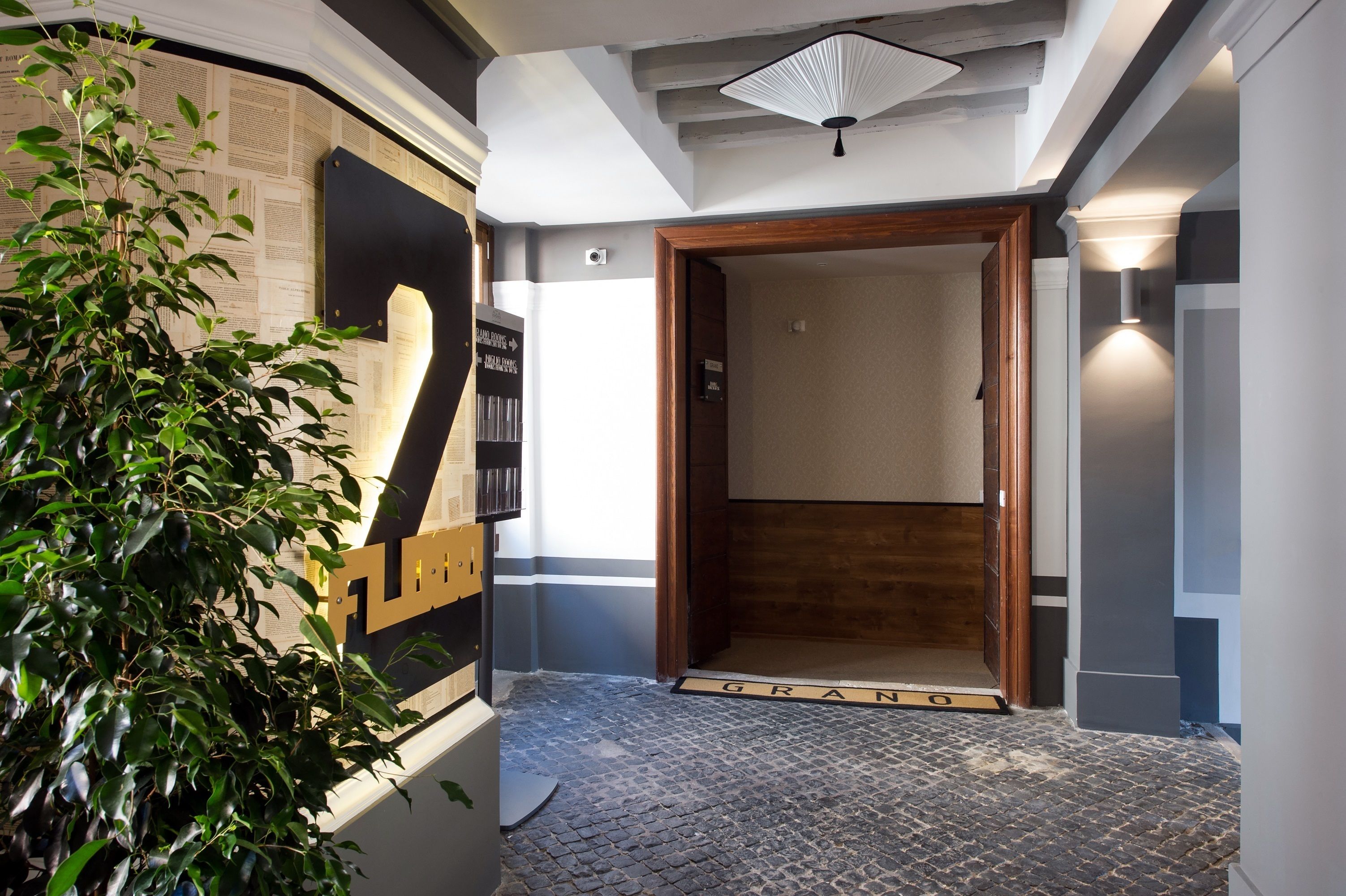 A hotel entrance with a wooden door, a doormat, and a wall-mounted sign.