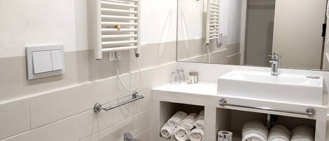 Une salle de bain moderne équipée de toilettes, d’un bidet, d’un lavabo et d’un espace pour ranger les serviettes.