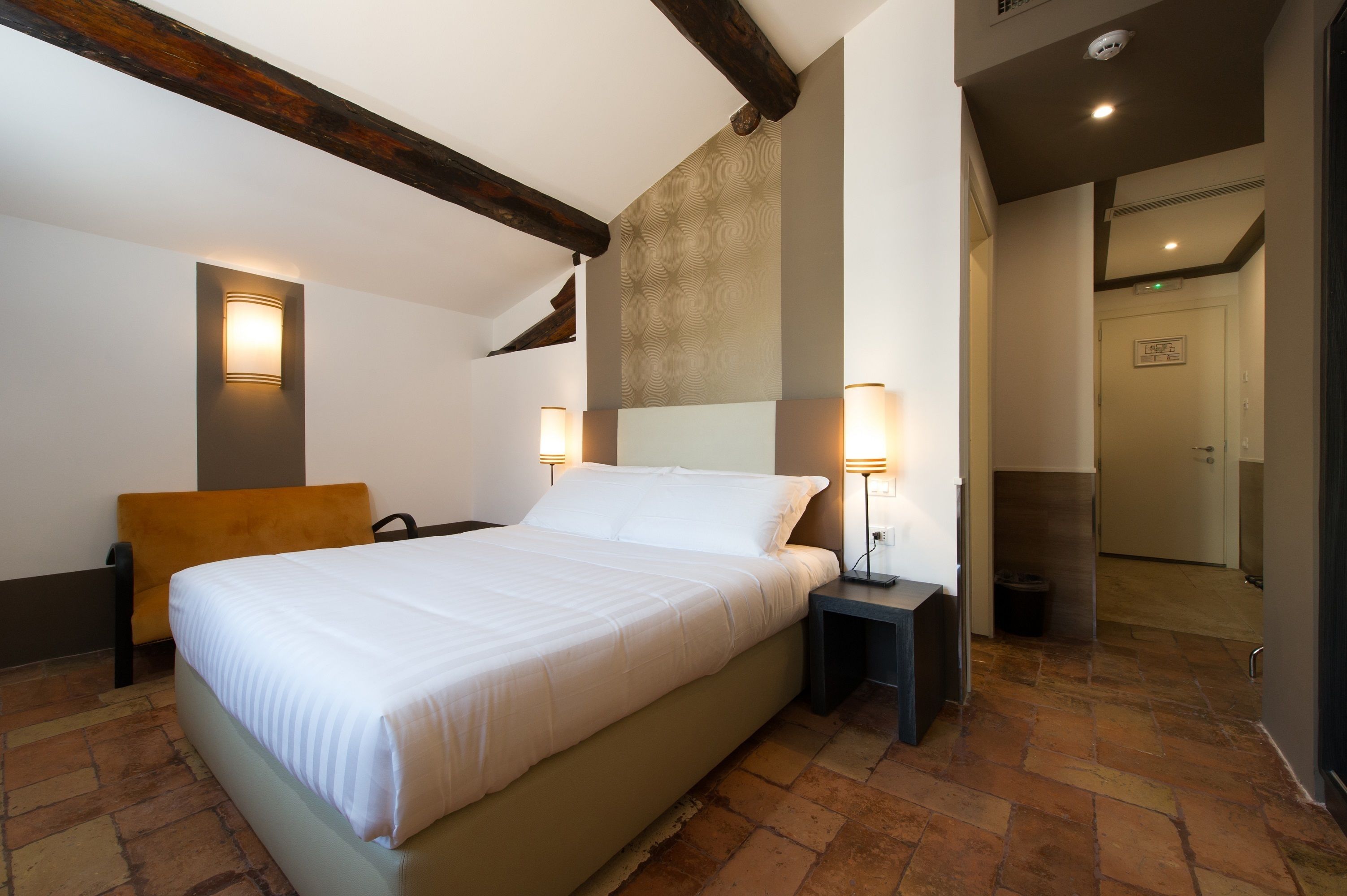 Un dormitorio con una cama, dos lámparas de noche, una mesita de noche y un cabecero de madera.