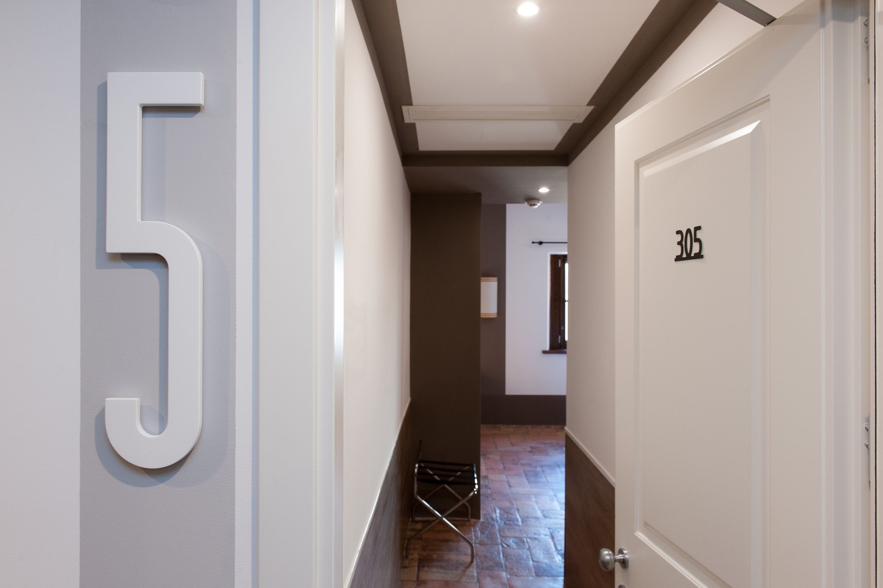 A hallway with a large '5' on the left wall, a door labeled '305' on the right, and a metal rack in the center.