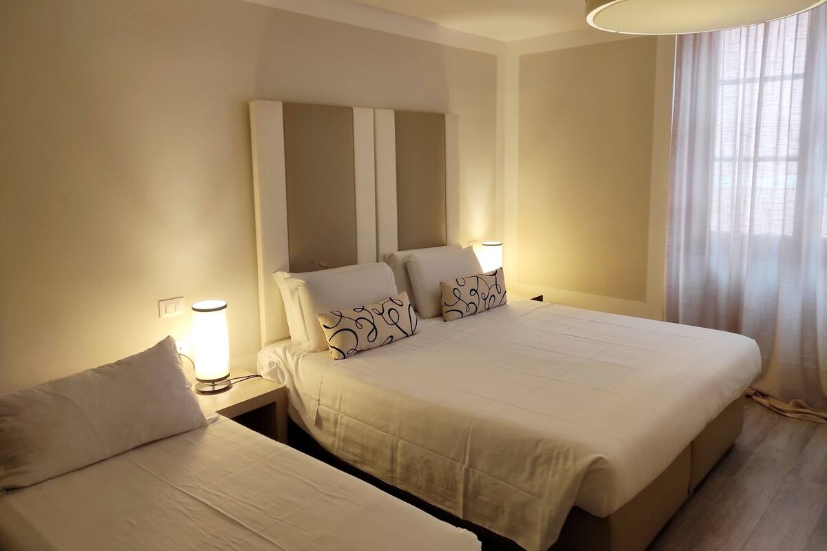 Una camera d'albergo con un letto grande, due comodini e una lampada su ciascun comodino.