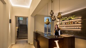 A modern kitchen with a central island, pendant lighting, and a bar area with shelves of bottles. - Avenue Legerova 19 (Prague)