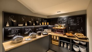 A breakfast bar with various food items and utensils, including eggs, sausages, and bread. - Avenue Legerova 19 (Prague)