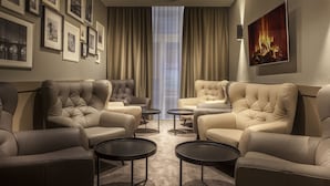 A modern hotel room with a seating area featuring two sofas and two small tables, framed pictures on the wall, and a large painting of a fire. - Avenue Legerova 19 (Prague)