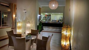 Un hall d’entrée avec des meubles en osier, un comptoir de réception et un luminaire suspendu.
