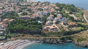 Vue aérienne d’une ville côtière avec une plage, des villas et un port de plaisance.