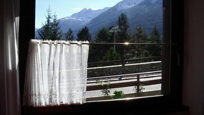 Janela com vista para uma cordilheira, guarda-corpo de varanda e cortina.