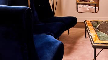 A room with a blue armchair, a floor lamp, a mirror, and a coffee table.