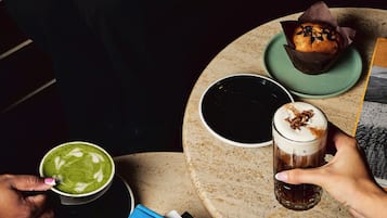 Una mesa con diversas bebidas y pastelería, incluyendo un croissant y un muffin.