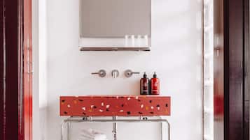 A bathroom with a mirror, a sink with soap dispensers, and a towel rack with folded towels.