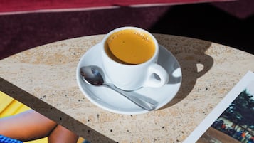 Une tasse de café sur une table, avec une cuillère, une photographie et un sac bleu.