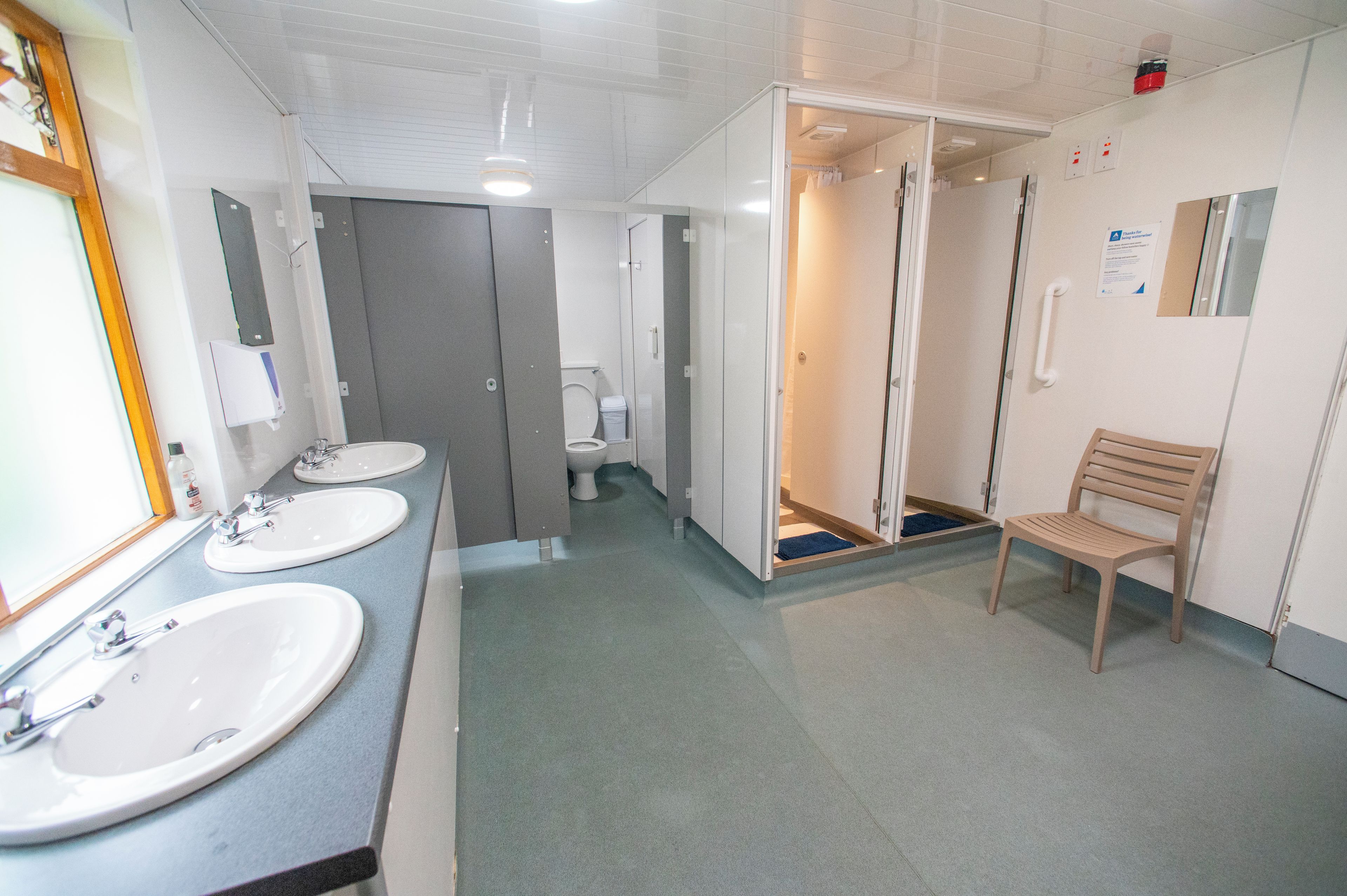 A public restroom with two sinks, a toilet, and a shower stall.