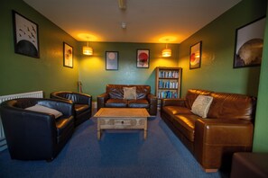 A living room with leather sofas, a coffee table, and a bookshelf.