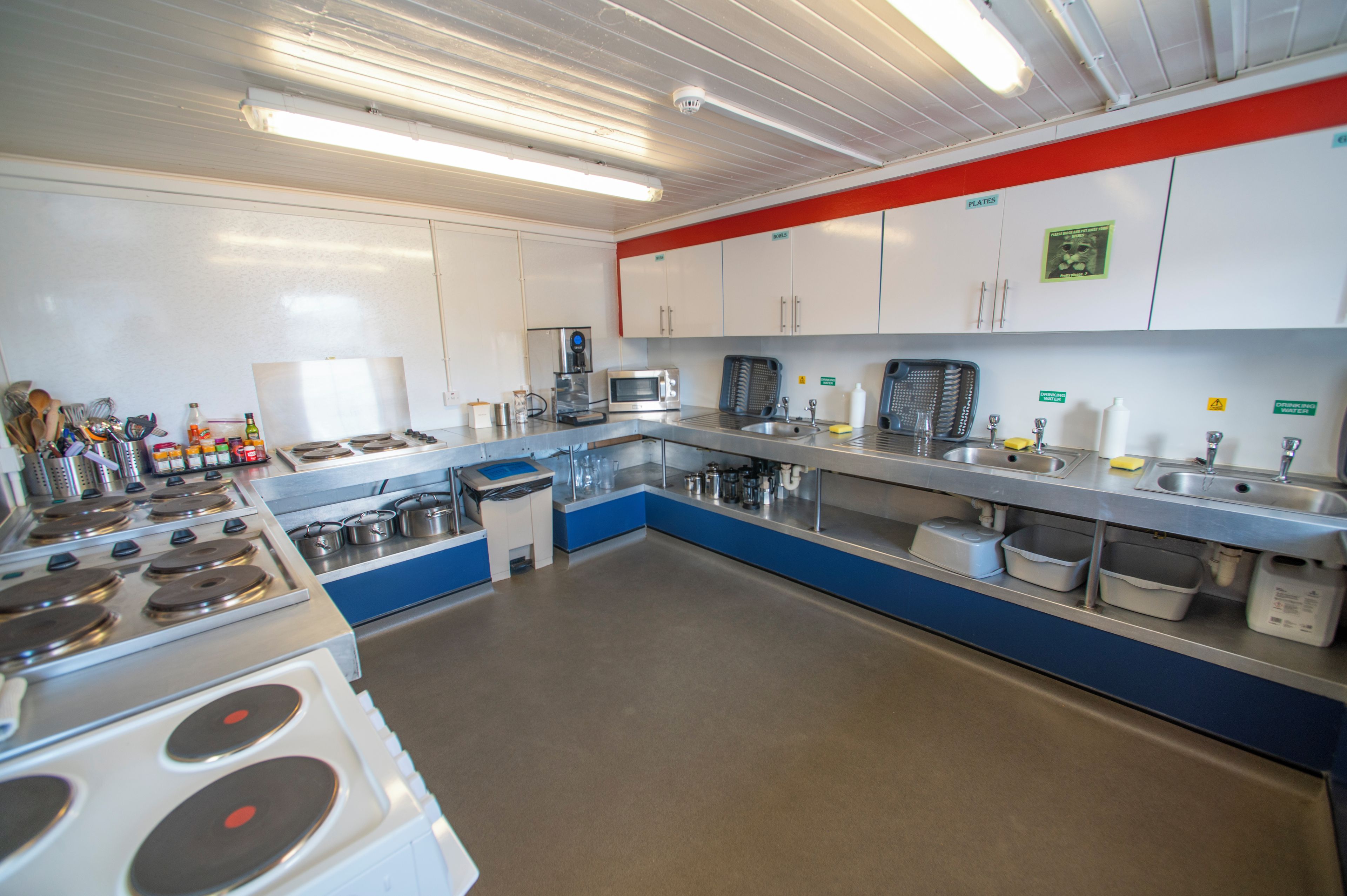 A commercial kitchen with stainless steel appliances, a microwave, and various cooking utensils.