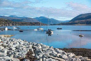 A rocky shoreline with calm water and boats.