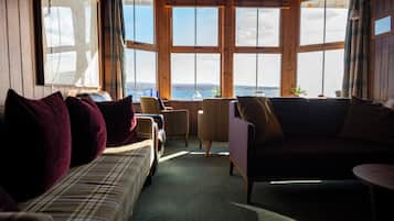 A cozy room with a large window, a sofa, a chair, and a small table.