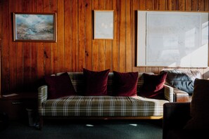 A wooden-paneled room with a plaid sofa, two framed artworks, and a large map on the wall. - Gairloch Sands Youth Hostel (Gairloch)