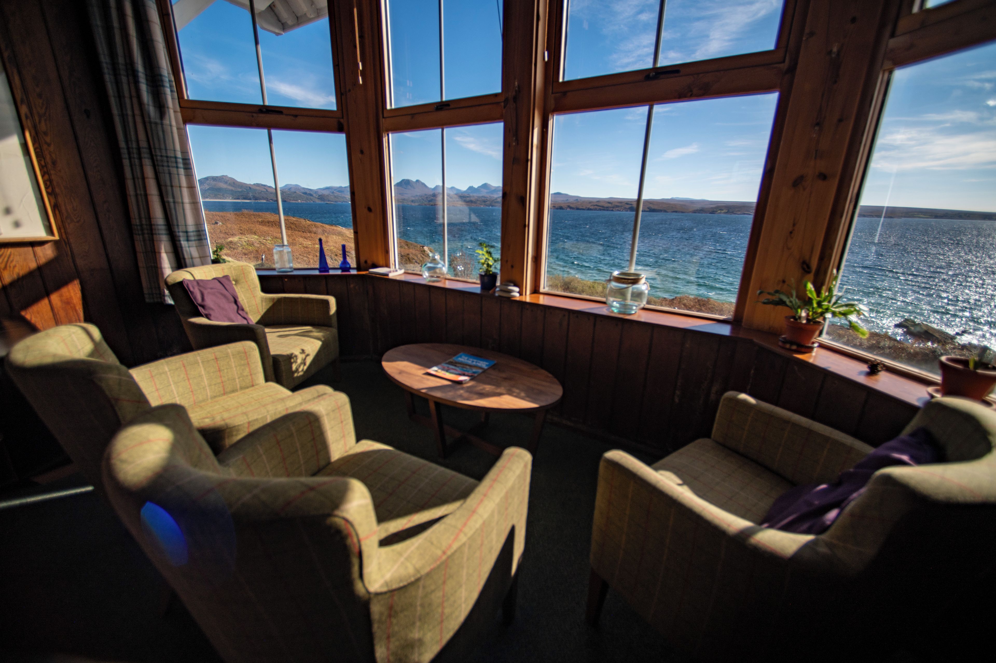 Una habitación con vista al mar, paredes de madera y una mesa redonda con sillas.