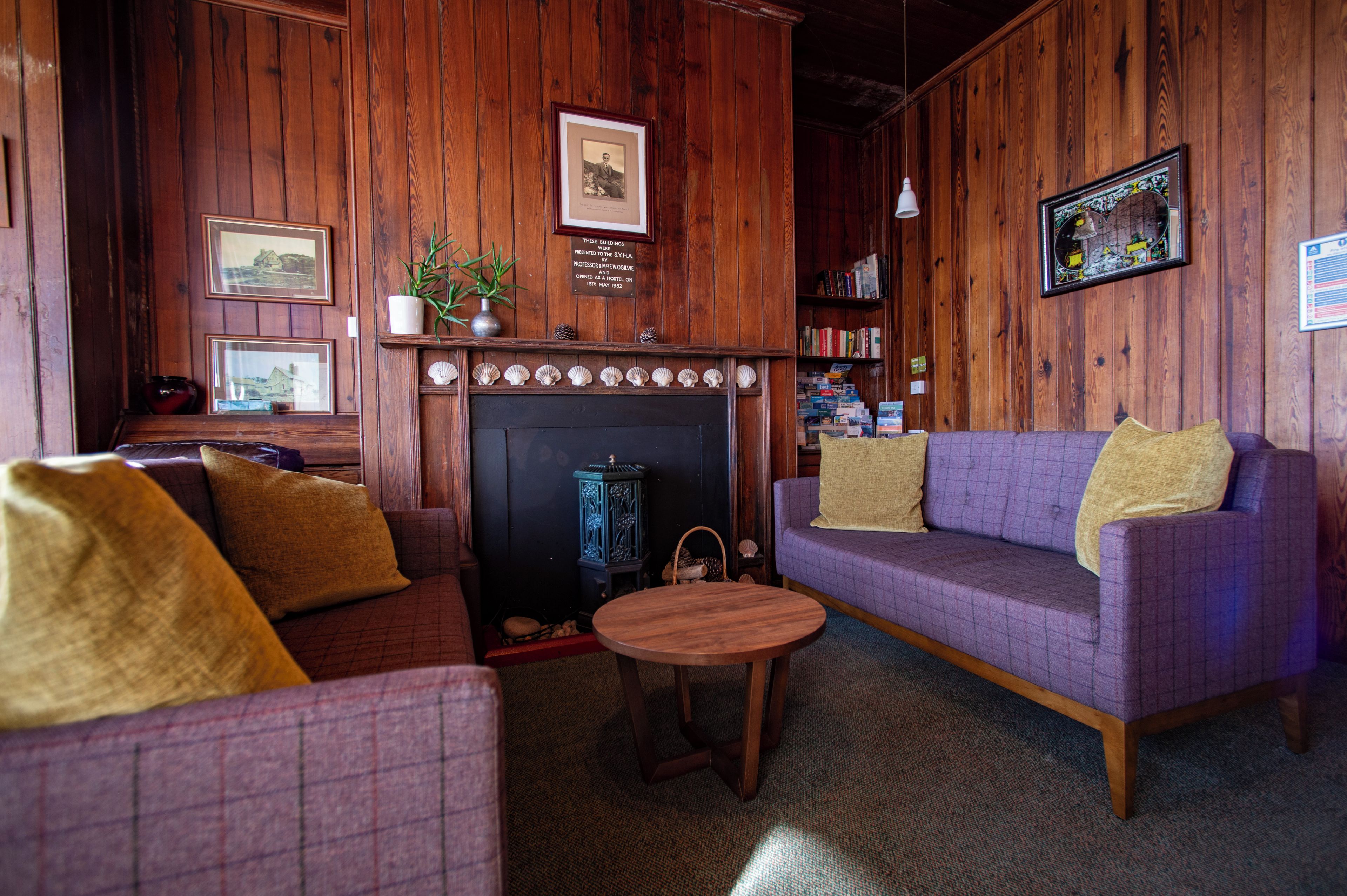 A cozy room with a fireplace, a sofa, a small table, and a bookshelf.