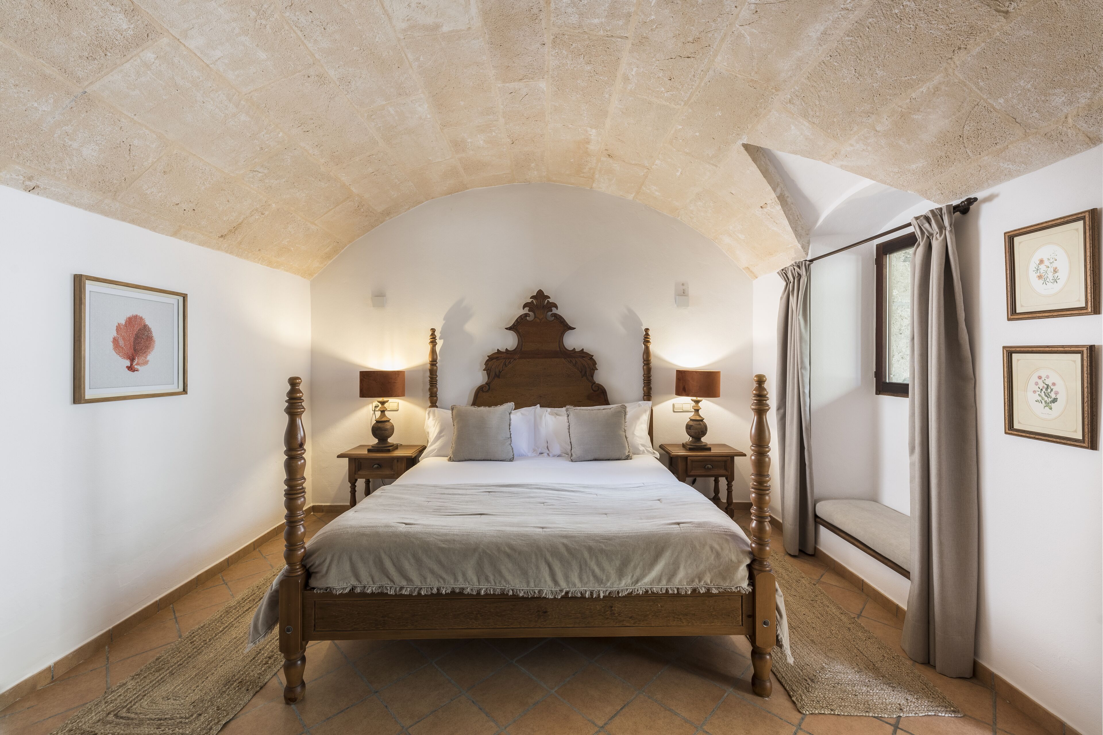 A bedroom with a large bed, two bedside tables, and a stone ceiling.