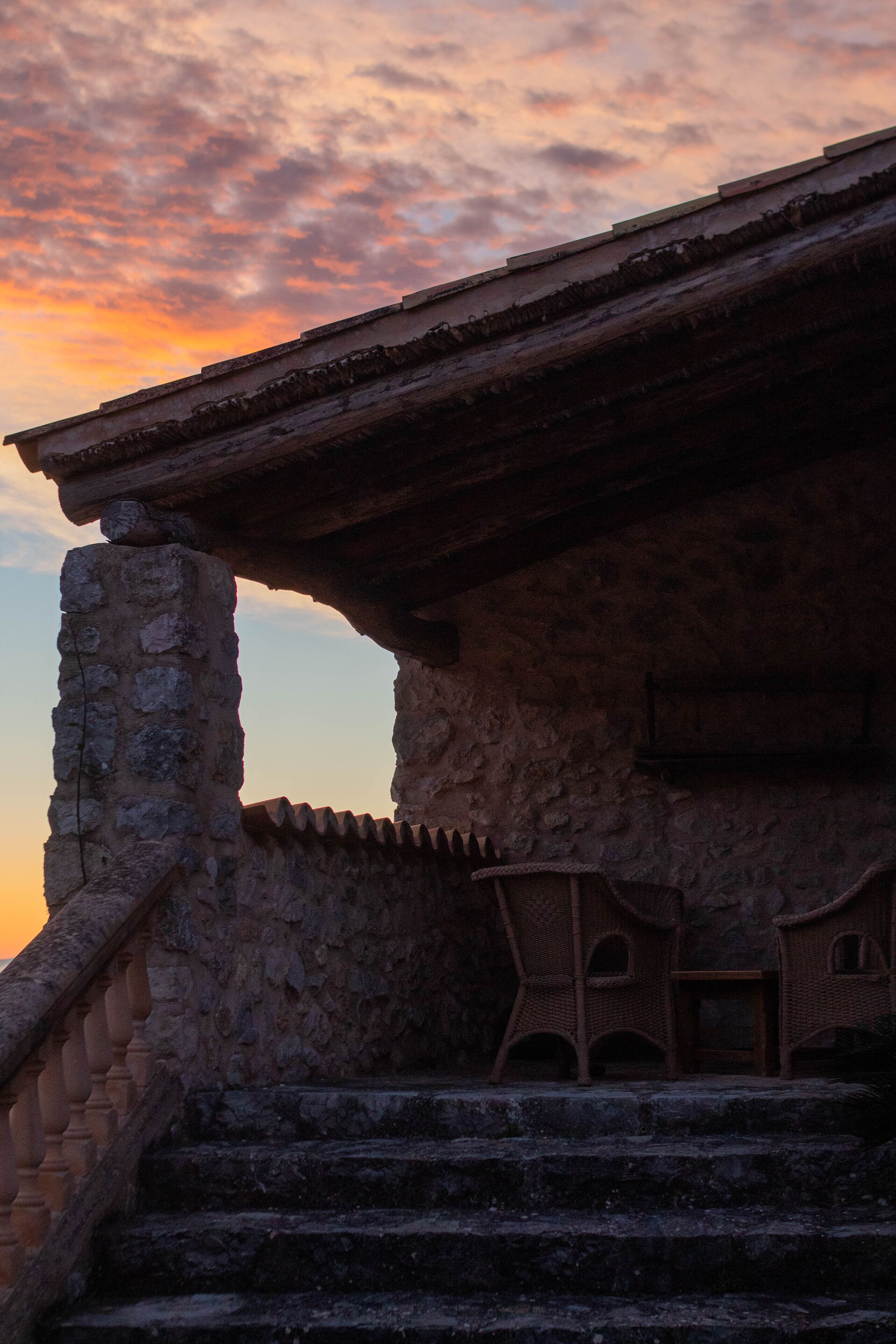 A stone building with a wooden staircase leading to a balcony.