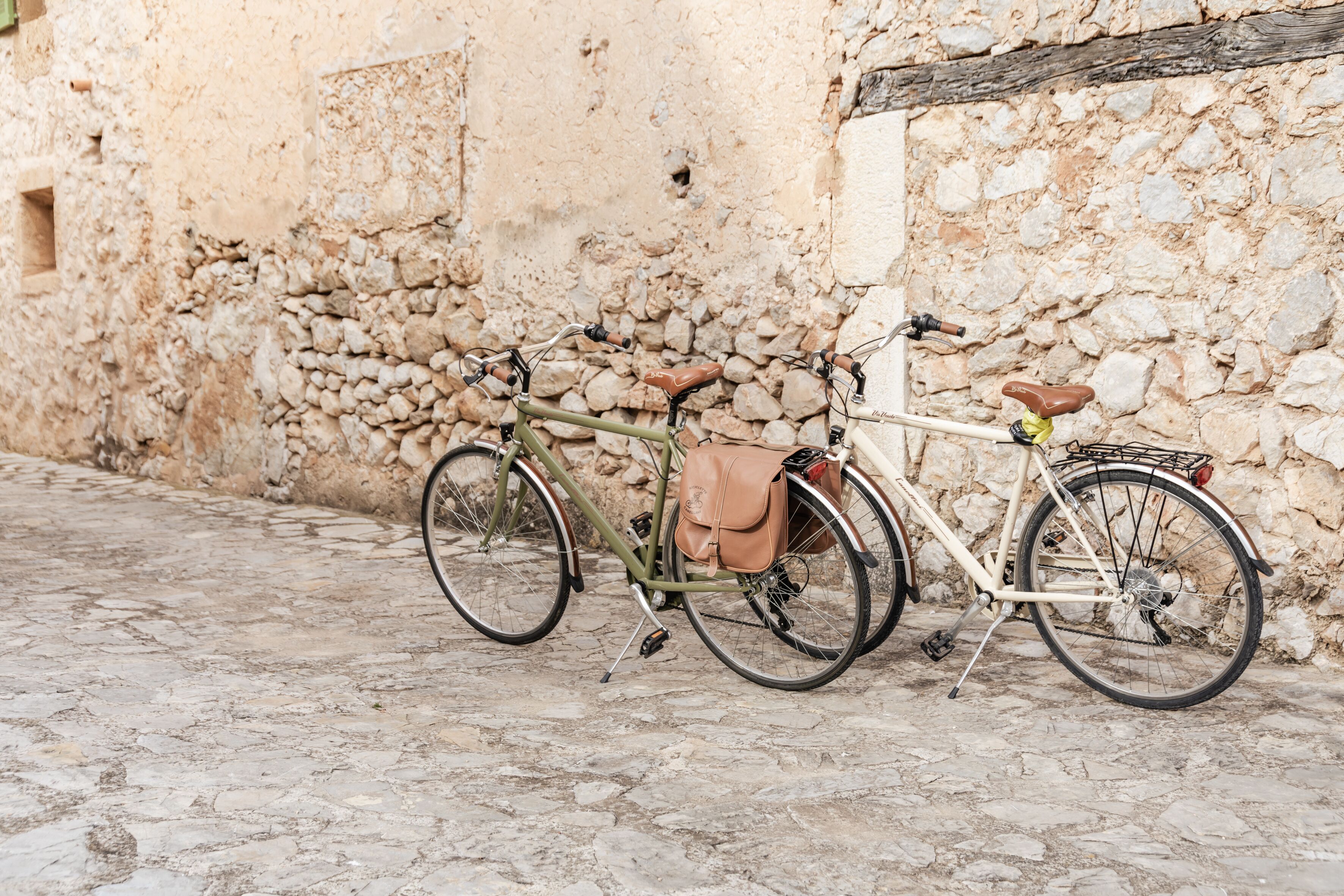 Dos bicicletas estacionadas frente a una pared de piedra.