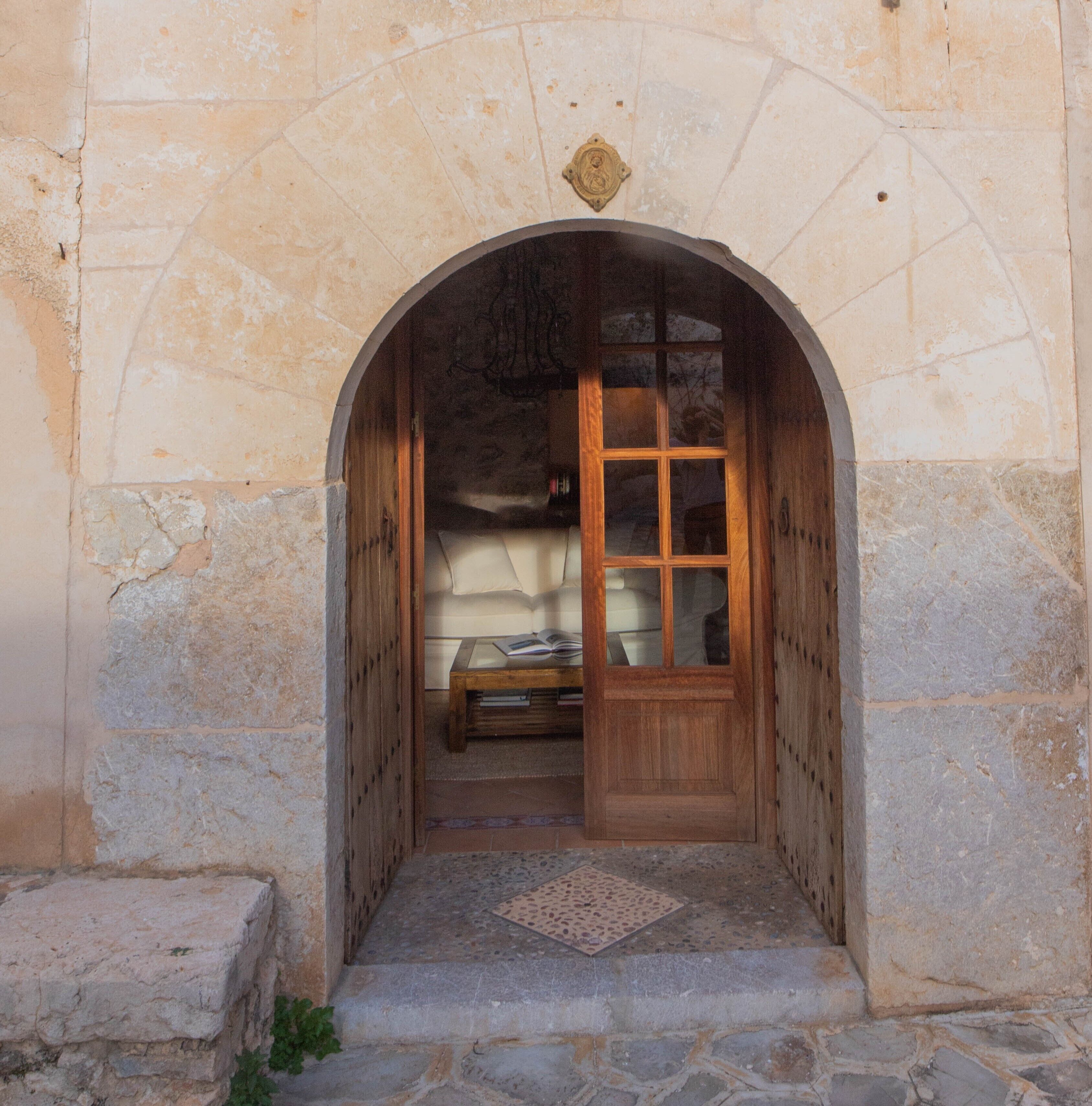 Un arco de entrada a una habitación con cama, una mesita y un adorno sobre la puerta.