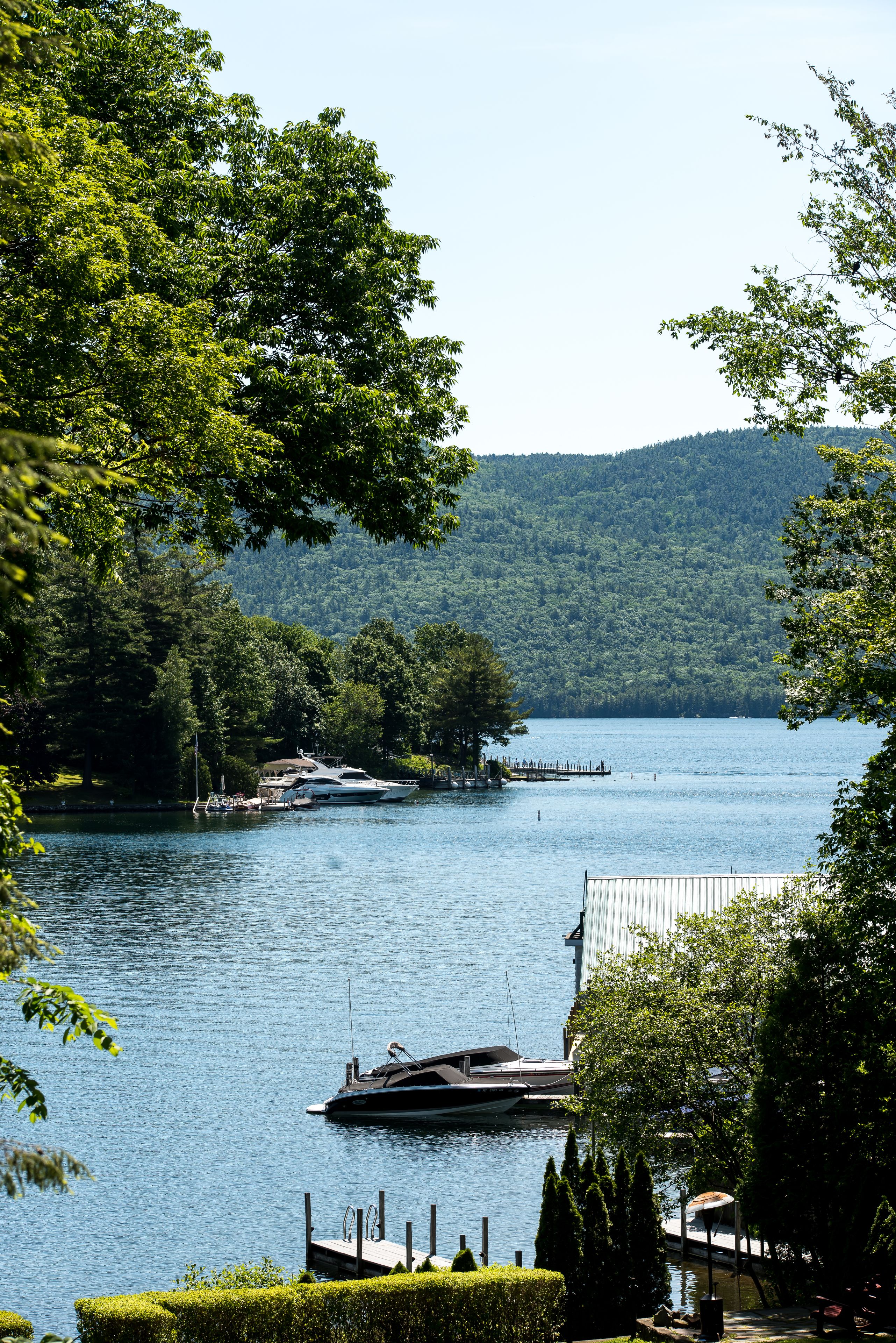 A lake with a dock and a boat, surrounded by trees and hills.