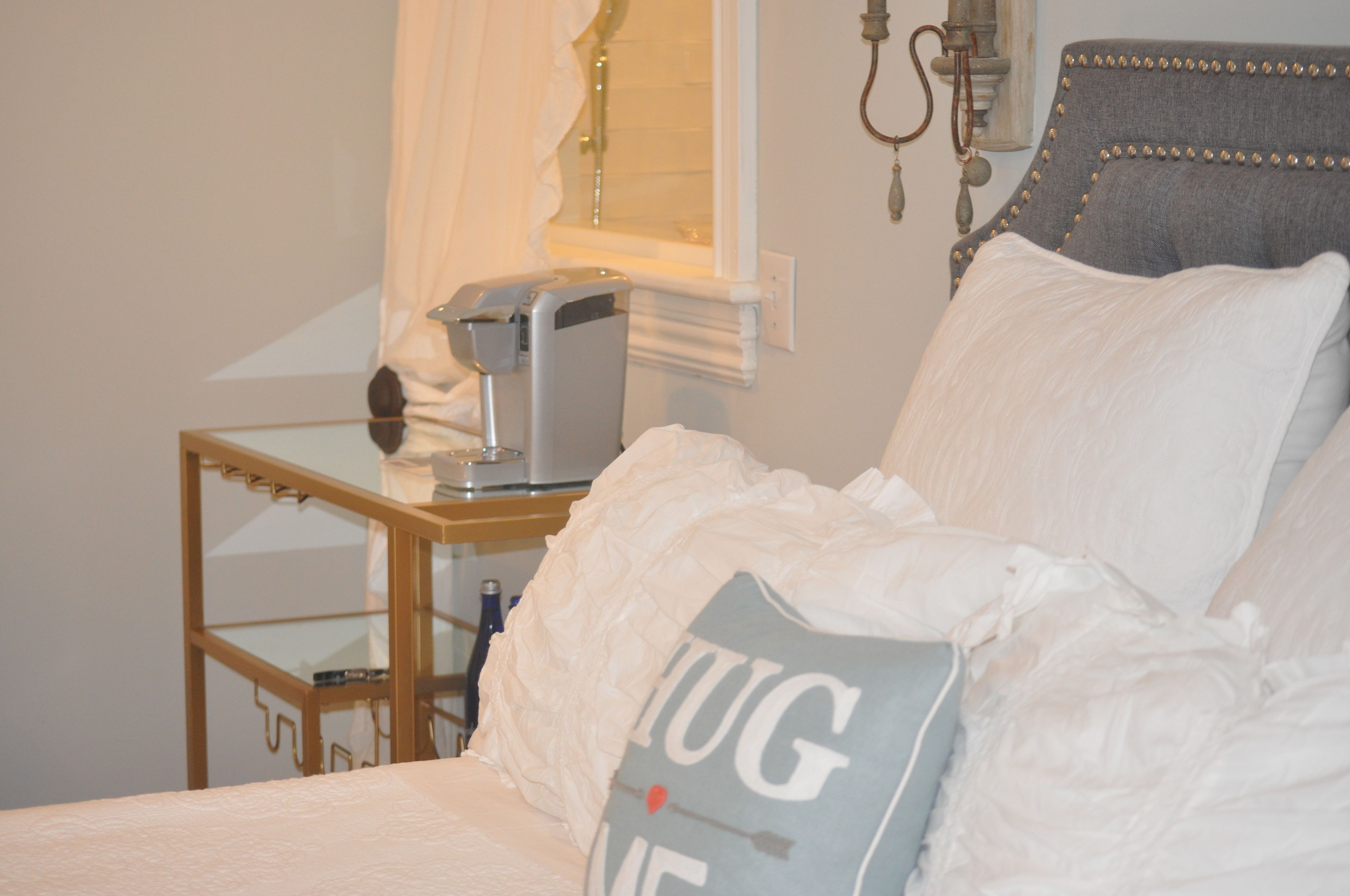 Une chambre à coucher avec un lit, une table de chevet, une lampe et une fenêtre avec des rideaux.