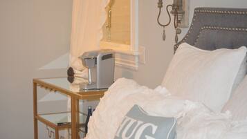 Une chambre à coucher avec un lit, une table de chevet, une lampe et une fenêtre avec des rideaux.