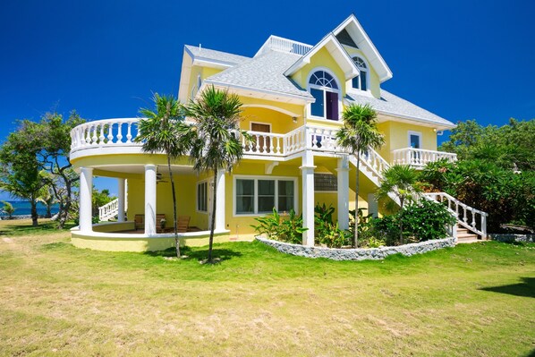 A two-story house with a balcony, a staircase, and a view of the ocean.