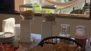 Un bufé de desayuno con pan, bollería y una rebanada de sandía.