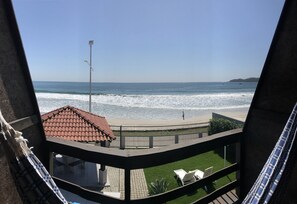 Un balcón con vista a la playa, un farol y una estructura de techo a la vista.