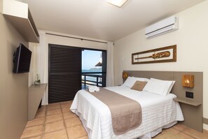 Un dormitorio de hotel con cama, televisión, aire acondicionado y vista al mar.