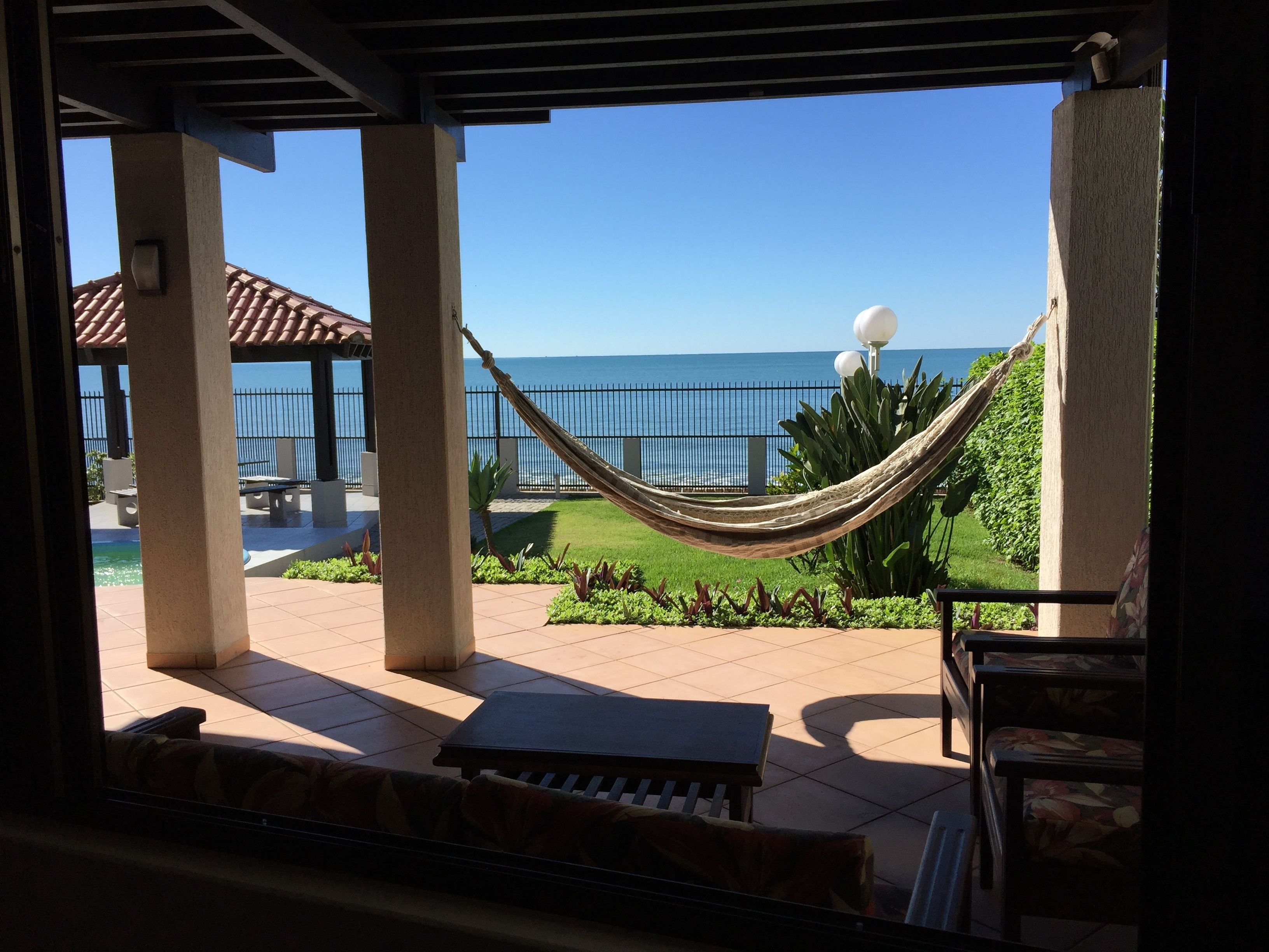Une terrasse avec un hamac, du mobilier d’extérieur et une vue sur l’océan.