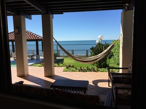 Un patio con una hamaca, mobiliario exterior y vista al océano.