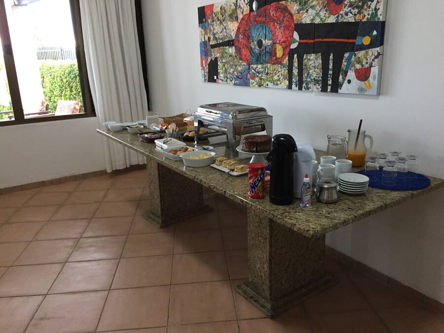 Un'impostazione per colazione a buffet con diversi cibi e bevande su un tavolo in granito, una macchina da caffè e un quadro appeso al muro.