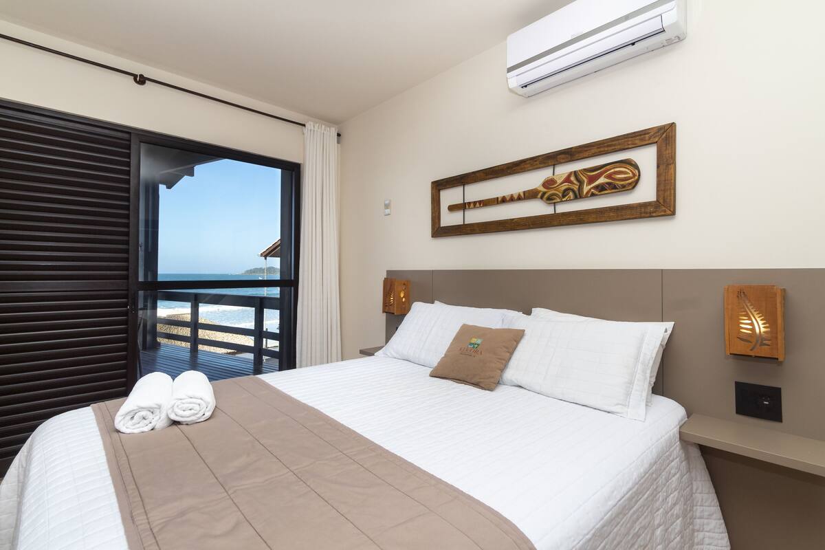 Una habitación de hotel con cama, vista al mar y una obra de arte de madera en la pared.