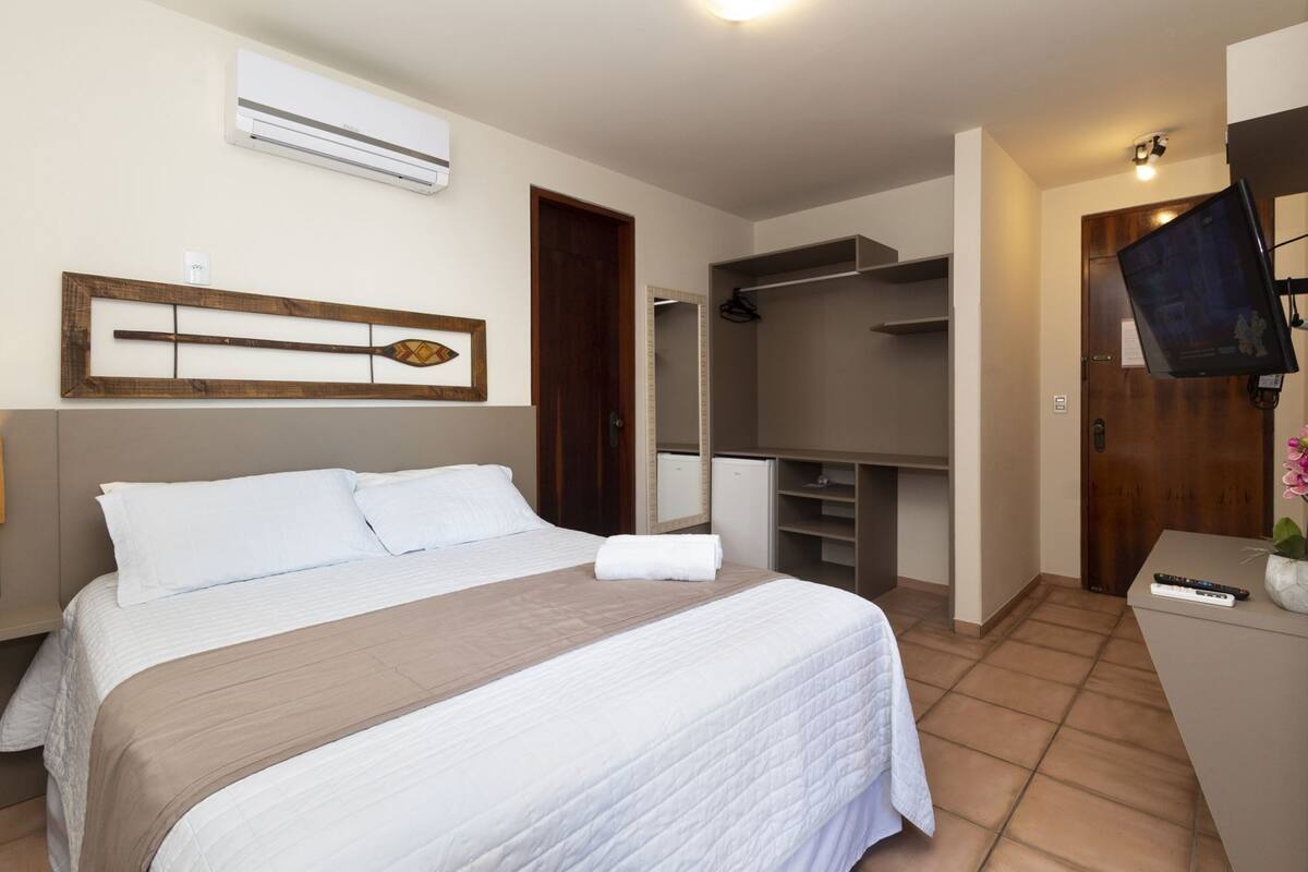 Un dormitorio con cama, armario, televisor y aire acondicionado.