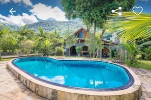 Una piscina al aire libre, sillones reclinables de piscina